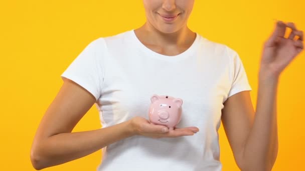 Улыбающаяся женщина кладет монеты в копилку, бюджет, сбережения на будущие инвестиции — стоковое видео