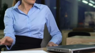 Resmi takım elbiseli genç bir kadın dizüstü bilgisayarı açıyor ve e-postaları okuyor, geceleri çalışıyor.