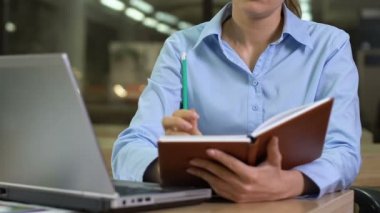 Genç bir kadın deftere fikirler yazıyor, iş günlerini düzenliyor, geleceği planlıyor.