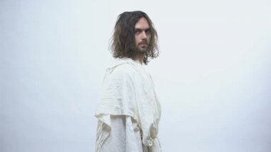 Beyaz cüppeli Tanrı kameraya dönerek, umut vermek için el kaldırarak, kutsama