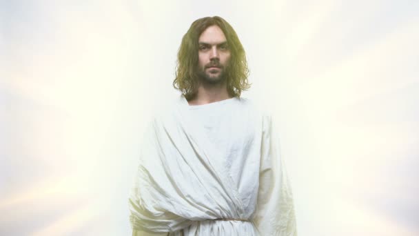 Милосердный Иисус смотрит в камеру на сияющем фоне, благодати Господней — стоковое видео