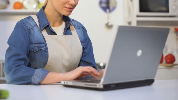 Female culinary specialist typing on laptop, keeping blog, giving cooking tips — Stock Video