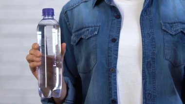 Plastik şişe tutan kadın ve yiyecek plastiğinden yapılmış kişisel su şişesi.