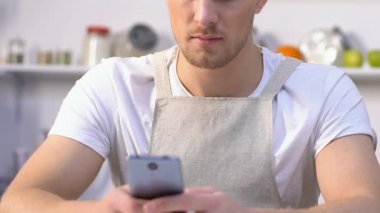 Kıskanç karısı kahve yapıyor ve kocasını gözetlemek akıllı telefonda sohbet ediyor