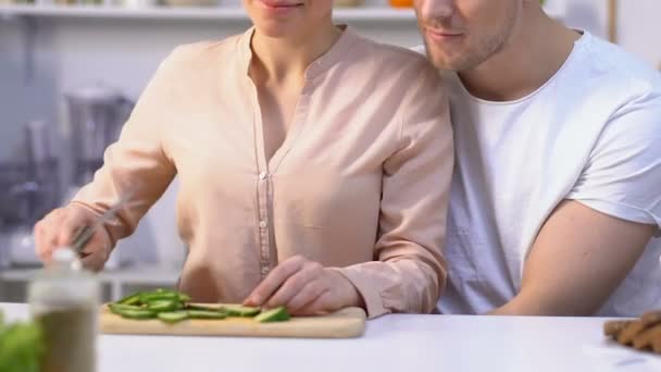 Chica atractiva alimentando a su amado novio verduras, feliz pareja en la cocina — Vídeos de Stock