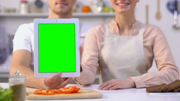 Симпатичная семейная пара, держащая планшет с зеленым экраном и показывающая большие пальцы вверх, ведущая блог — стоковое видео