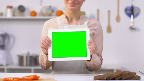 Счастливая женщина показывает зеленый экран планшет на камеру, онлайн рецепты применения — стоковое видео
