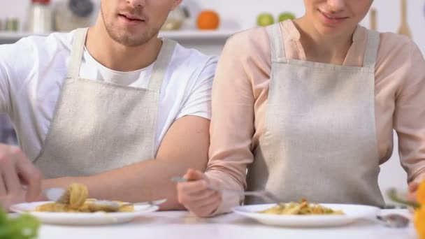 Atractivo marido y mujer en delantales tratando de espaguetis hechos a sí mismo, cocina familiar — Vídeos de Stock