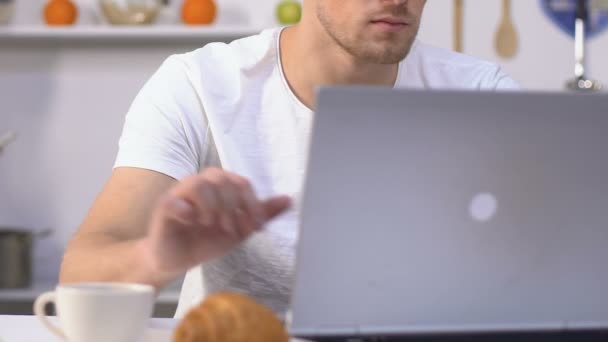 Мужчина работает на ноутбуке пьет кофе, жена по телефону во время приготовления ужина — стоковое видео