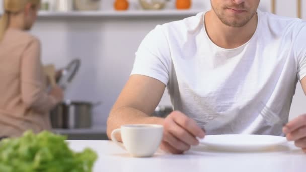 Hambriento esposo impaciente sosteniendo cuchillo y tenedor esperando comida de esposa lenta — Vídeos de Stock