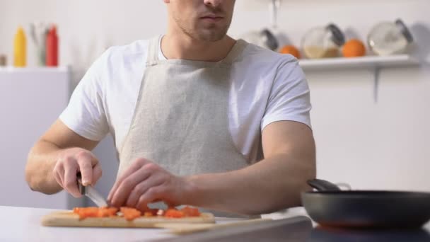 Мужчина профессионально режет помидоры и подбрасывает сковородку, чтобы смешать ингредиенты — стоковое видео