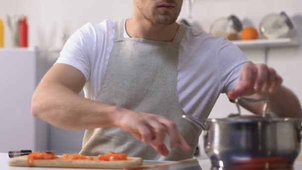 Чоловік намагається соусом в сковороді і прикручує обличчя через поганий смак, приготування їжі — стокове відео