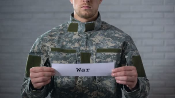 Palabra de guerra escrita en señal en manos de soldado, conflicto armado, víctimas — Vídeo de stock