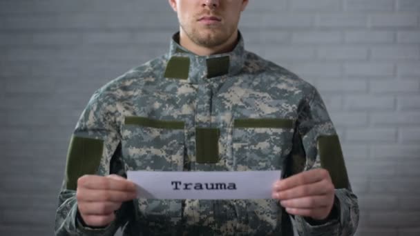Травматическое слово, написанное на знаке в руках солдата мужского пола, повреждение тела, здоровье — стоковое видео