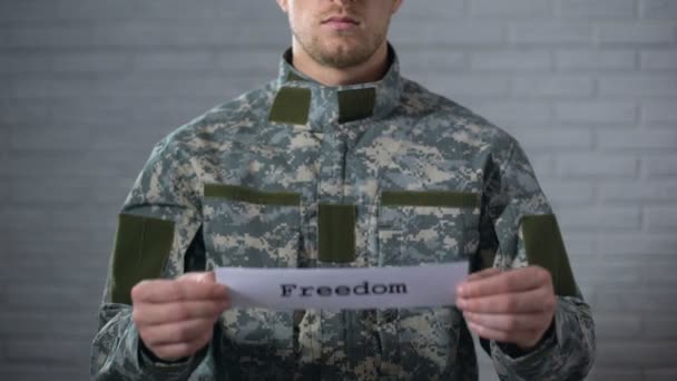 Η λέξη ελευθερία γραμμένη στην πινακίδα στα χέρια του αρσενικού στρατιώτη, της ειρήνης, του τέλους του πολέμου — Αρχείο Βίντεο