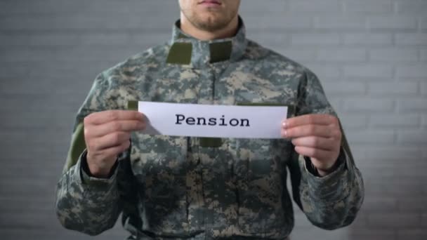 Пенсионное слово написано на вывеске в руках солдата-мужчины, пенсионные выплаты — стоковое видео