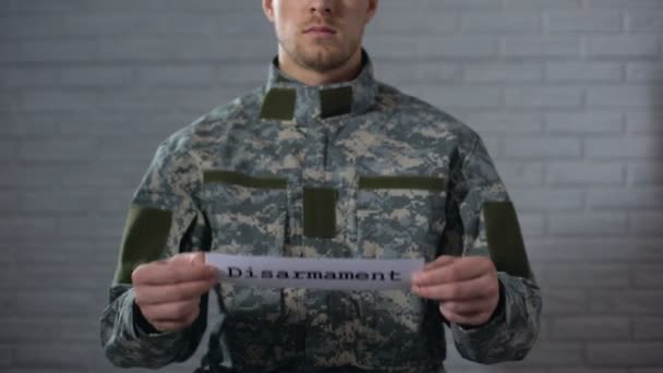 Disarmament word written on sign in hands of male soldier, end of war, peace — Stock Video