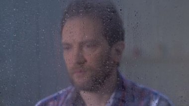 Depresif orta yaşlı erkek yağmurlu pencerede bakıyor ve düşünme, yalnızlık