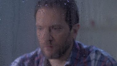 Yağmurlu pencerearkasında umutsuzluk içinde avuç içi ile pensive erkek kapanış yüzü, sorunlar