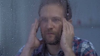 Depresif adam güçlü migren acı, masaj tapınaklar, yağmur bakarak