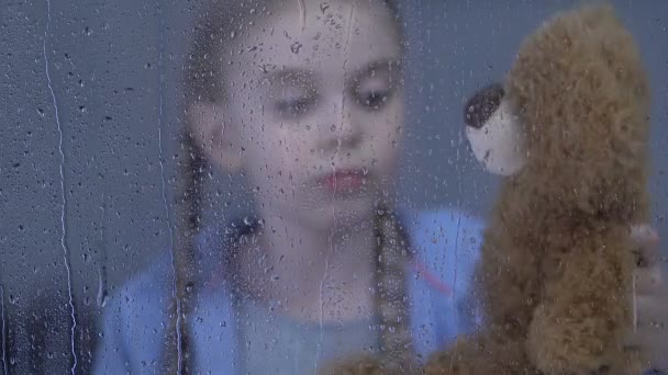 Красивая девушка играет с любимым плюшевым мишкой страдает одиночеством и издевательствами — стоковое видео