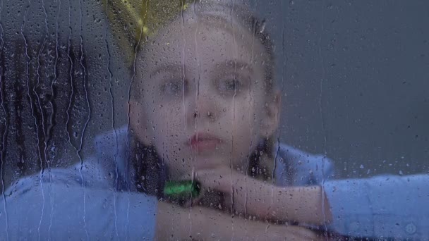 Deprimido chica jugando con partido ventilador detrás de lluvia ventana, intimidación víctima — Vídeos de Stock