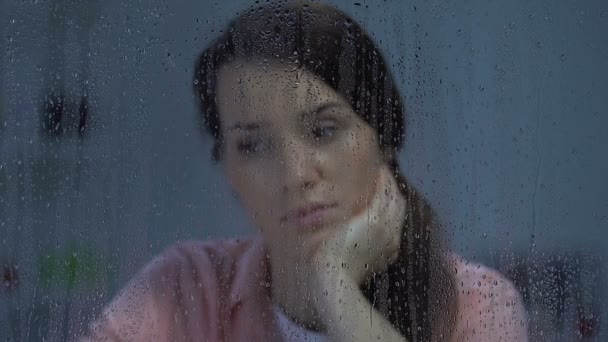 Депресивна леді середнього віку, яка дивиться у дощове вікно, страждає самотністю — стокове відео