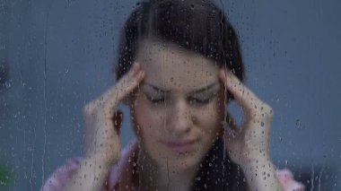 Lady güçlü baş ağrısı acı, masaj tapınaklar ve yağmurlu pencerede bakarak
