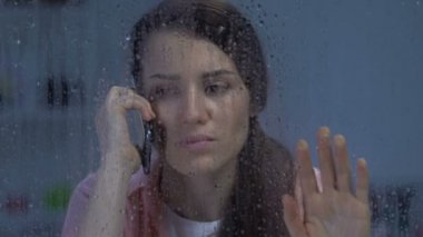 Üzgün kadın telefonda konuşurken, yağmurlu günde kötü haber alma, depresyon