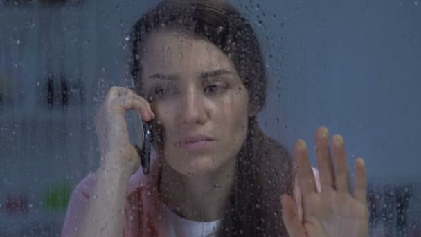 Upset female talking on phone, receiving bad news on rainy day, depression — Stock Video