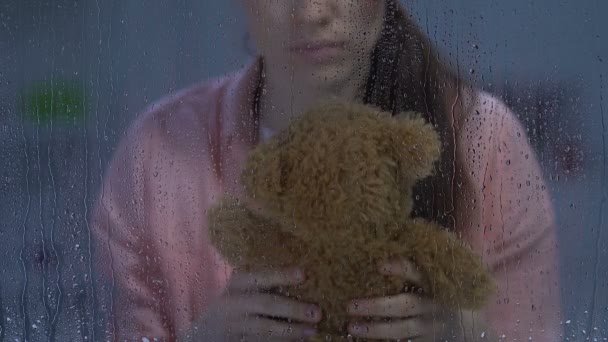 Sad female with wound on cheek hugging teddy bear, remembering happy childhood — Stock Video