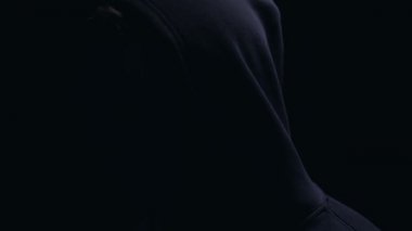 Kapüşonlu anonim maske kameraya yüz dönüyor, tanınmaz suçlu