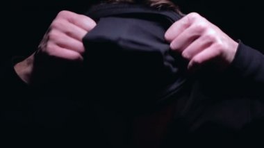 Ciddi adam balaclava giyen terör eylemi için hazırlanıyor, siyah arka plan