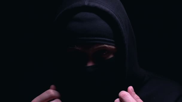 Hooded man in Balaclava kijken naar camera, klaar voor illegale actie, misdaad — Stockvideo