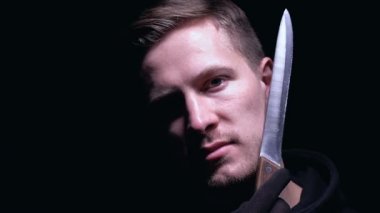 Gülümseyen bıçakla kurbanı tehdit, siyah arka plan üzerinde izole