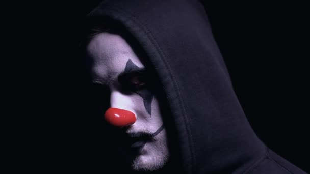 Mad maniak met clown gezichtsmasker wenden zich tot de camera, het vasthouden van pistool in handen, misdaad — Stockvideo