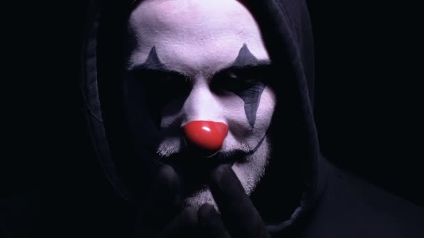 Сумасшедший маньяк в маске клоуна думает о следующей жертве, планирует убийство — стоковое видео
