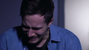 Genç adam umutsuzca ağlıyor, yas tutuyor ya da can sıkıntısı çekiyor, yakın plan.
