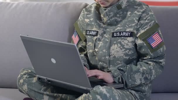 Female american soldier browsing internet site by laptop sitting sofa, research — Stock Video