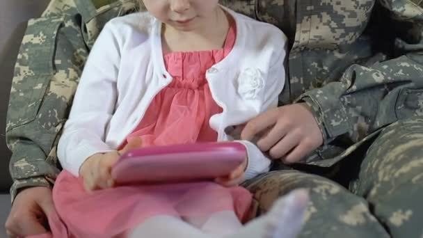 Мать в камуфляжной форме обучения дочери использовать игрушки таблетки, семейный досуг — стоковое видео