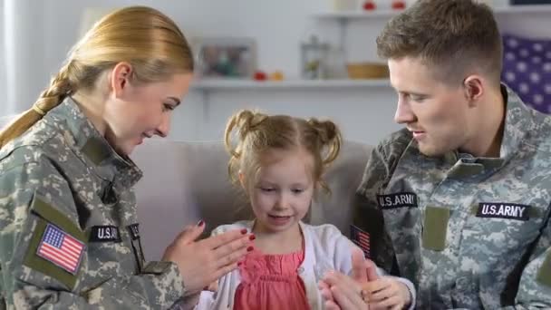 Joven madre y padre en uniforme militar jugando a la torta con su hija — Vídeo de stock