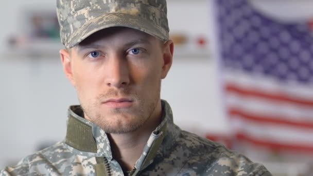 Confident serviceman looking camera, national flag on background, american army — Stock Video