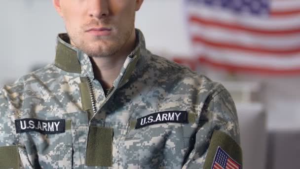 Brave military veteran in camouflage uniform with stripes, flag on background — Stock Video