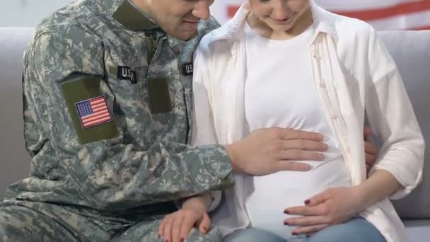 Joven soldado y esposa esperando sonriendo en la cámara acariciando el vientre, futuro seguro — Vídeos de Stock