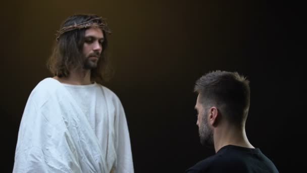 Сын Божий держит за руки молящегося человека, духовную поддержку, отпущение грехов — стоковое видео