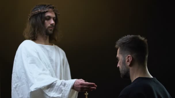 Jesus na coroa de espinhos dando colar cruz de madeira ao homem orante, esperança — Vídeo de Stock