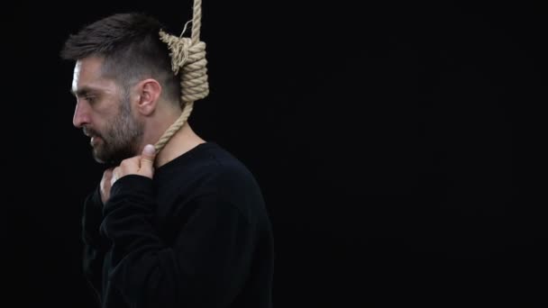 Disappointed man in rope noose on black background, life crisis, depression — Stock Video