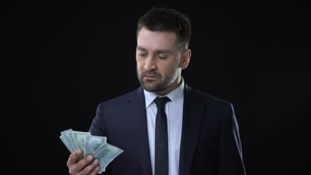 Confident rich man crumpling dollar bills on black background, independence — Stock Video