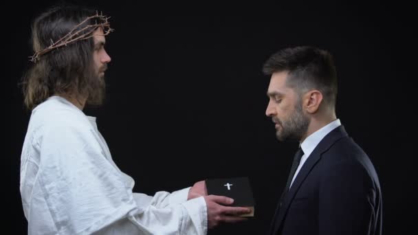Jezus Christus geeft de Bijbel aan zakenman, morele waarden, religieuze vriendelijkheid — Stockvideo