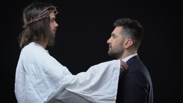 Прощающий Христос возлагает руку на плечо бизнесмена, смотрит друг на друга, верит — стоковое видео